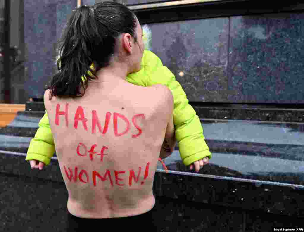 A FEMEN activist protests with her infant daughter outside the office of Ukraine's president on January 27. The topless woman was protesting a regulation that came into force in late 2021 requiring females between the ages of 18-60 from a variety of professions to register with Ukraine's military. In the event of an invasion, the women could be mobilized to aid in a war effort.