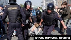 Russian policemen detain opposition supporters during a protest rally in Moscow on May 5. 