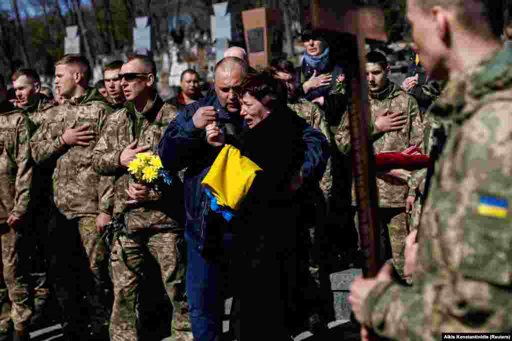 The mother of slain Ukrainian Senior Lieutenant Pavlo Chernikov is pictured as soldiers sing the Ukrainian national anthem at the Lychakiv cemetery in Lviv on March 28. 
