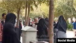 تصویری از درگیری که فرد روحانی با عصا به زن معترض حمله میکند