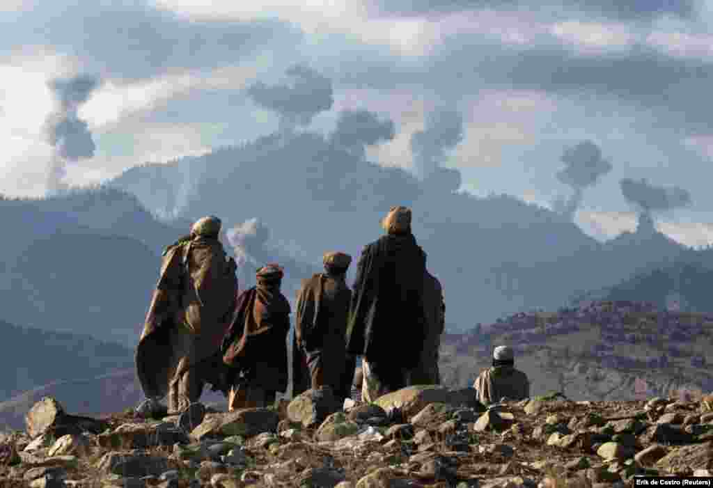 Afghan fighters watch explosions from U.S. bombs rock Afghanistan’s Tora Bora mountain complex in December 2001. When the United States invaded Afghanistan in the wake of the September 11 attacks, a massive aerial assault backed by ground fighters was launched on a series of mountain caves known as Tora Bora. Bin Laden and his Al-Qaeda fighters were believed to be hiding inside Tora Bora in those mountains before he escaped to Pakistan.