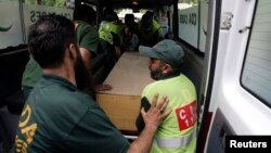 Hospital staff and rescue workers move the body of one of the 10 foreign tourists killed by gunmen near the Nanga Parbat peak in northern Pakistan. 