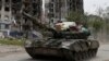 Военнослужащие пророссийских войск проезжают на танке по улице мимо разрушенного жилого дома в городе Попасная Луганской области. Украина, 26 мая 2022 года