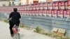 Велосипедист поминува покрај постери на владејачката партија за предвремените избори 2011. 