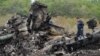 Responders stand amid aircraft parts at the crash site one day after Malaysia Airlines Flight MH17 crashed on July 19, with 298 people from 11 countries aboard, in a field near the town of Shaktarsk, in rebel-held eastern Ukraine.