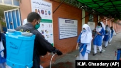 A worker disinfects the shoes of students upon their arrival at a school in Lahore. Infection numbers have spiked since schools reopened in mid-September. 
