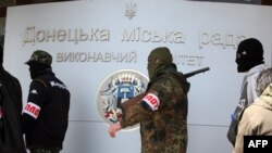 Armed pro-Russia activists walk outside the city state building they seized in the eastern Ukrainian city of Donetsk. So far, they have shown no sign of budging.