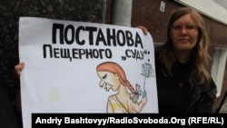A Lutsenko supporter holds a placard that accuses the court of holding a staged production.