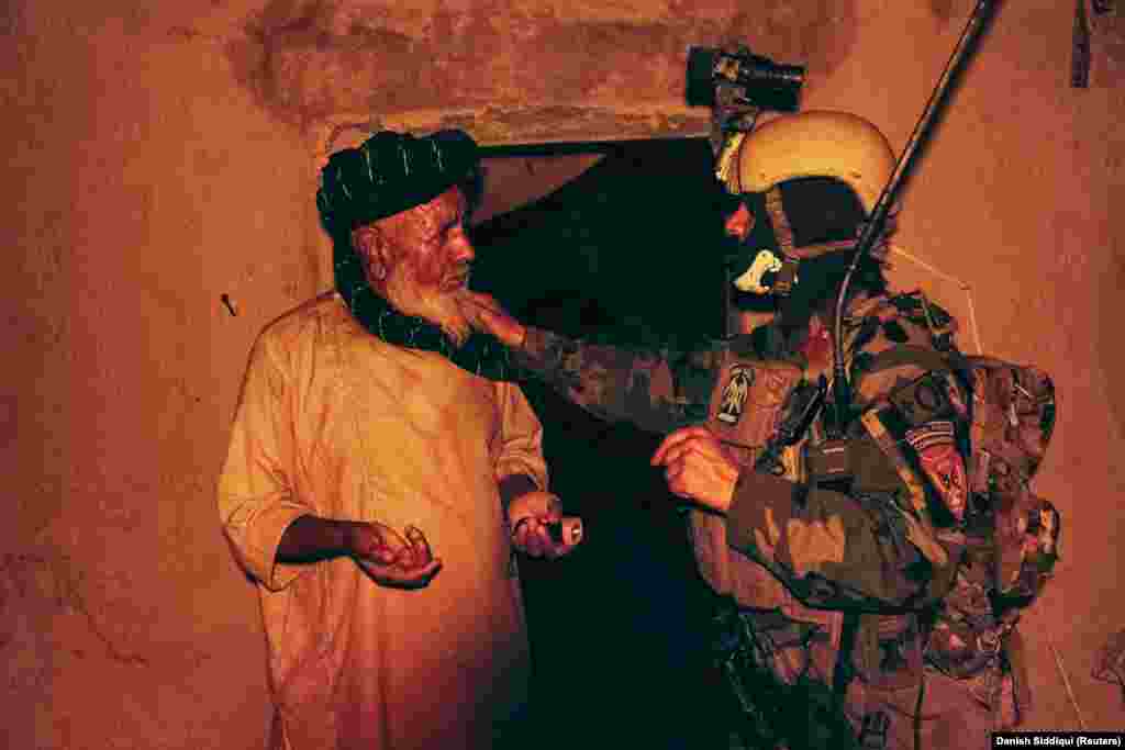 A special forces soldier speaks to a resident as others search his house during the anti-Taliban operation on July 12. 