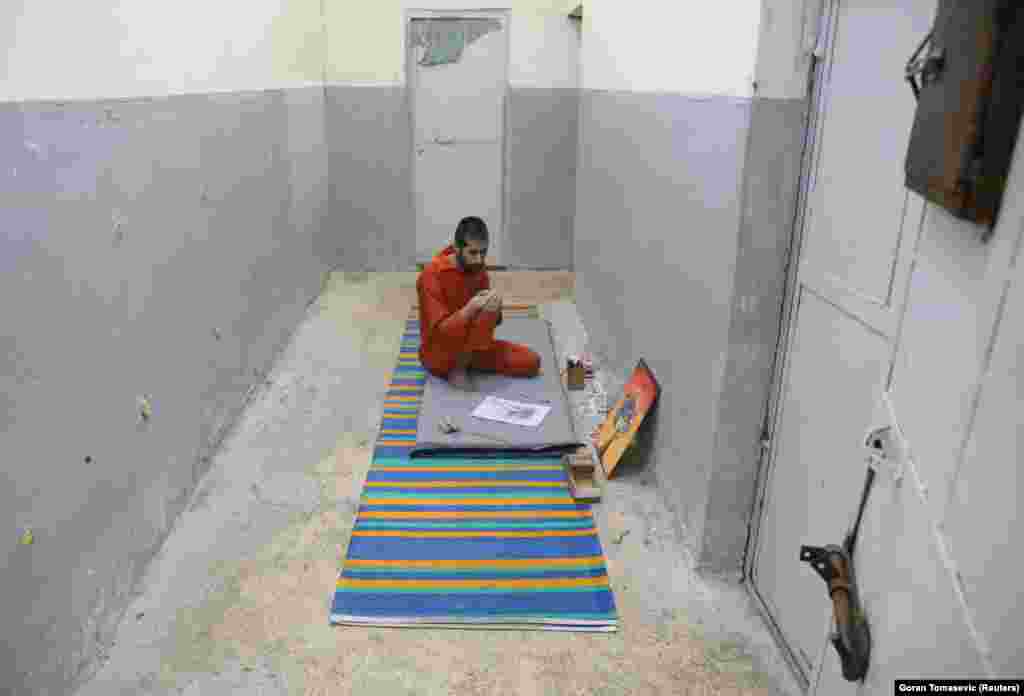 Abed El-Hamed Atiya, an Iraqi prisoner suspected of being part of the Islamic State group, sits next to a picture he drew inside a prison in Hasaka. He is kept apart from other prisoners, some of whom strongly object to his art. 