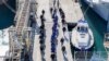 Мигранти придружувани од италијанската полиција во пристаништето Шенѓин, северозападна Албанија, на 28 јануари 2025 година.
