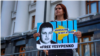 Vladyslav Yesypenko's wife, Kateryna, stands with a poster in his support near the office of the Ukrainian president in July.