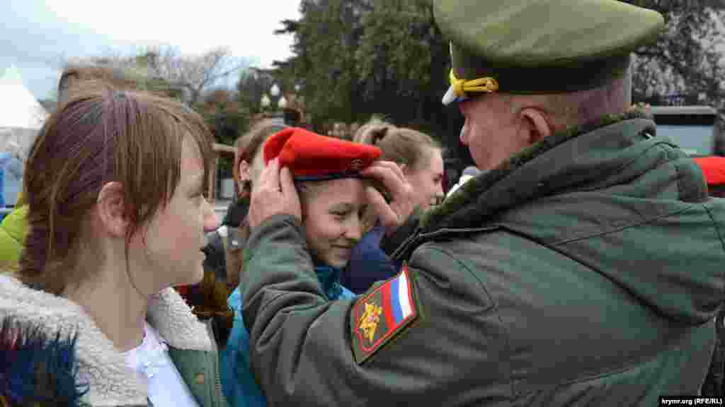 A girl receives a beret as part of her Yunarmiya uniform.&nbsp;