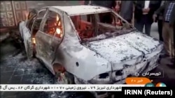 People stand near a burning car in Tuyserkan, Hamadan Province, on December 31.