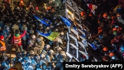 Riot police storm a barricade at Independence Square.