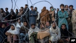 د تورخم په یوه کمپ کې راستانه شوي افغان کډوال نوم لیکنې ته ناست دي (آرشیف)