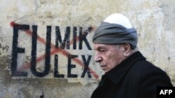 A Kosovar Albanian man walks in front of anti-EU and UN graffiti in the capital, Pristina, in late November.