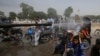 A volunteer sprays water on people to keep them cool as temperatures reached 44 Celsius in Karachi on May 21.