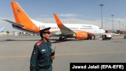 An Afghan police officer stands guard in front of a Boeing 737-500 of the Afghan carrier Kam Air at Kabul International Airport in Kabul. (file photo)