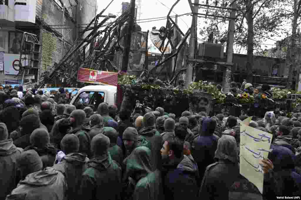 The funeral procession of a Islamic Revolutionary Guards Corps member killed in the recent protests in Shahriar, on the western edge of Tehran. Buildings in the background were also damaged in the protests. 
