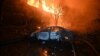 A burnt car is pictured in front of a burning house following a Russian drone strike in Kharkiv, Ukraine, on June 11.
