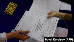 A woman receives her ballot paper at a polling station in Vladivostok on June 25.