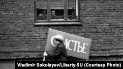 O femeie se grăbește la o demonstrație, pe strada Obnorskogo, Novokuznetsk. 1 mai 1983. Pe pancartă scrie „ Fericire”