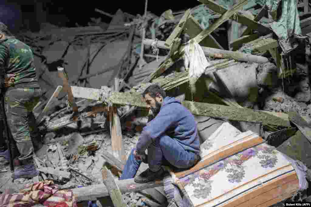 A resident sits amid the rubble as rescuers search for his relatives after a rocket hit a residential area in Ganca, Azerbaijan’s second-largest city, on October 17.