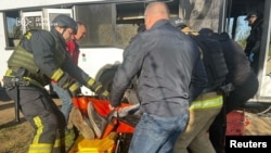 Ukrainian rescuers evacuate a wounded person from a bus damaged by a Russian drone strike in the town of Marhanets, in the Dnipropetrovsk region, on April 23.