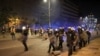 Новинари со шлемови и гас-маски зад полицајци на протест во Белград, Србија, 15 август 2025 година.