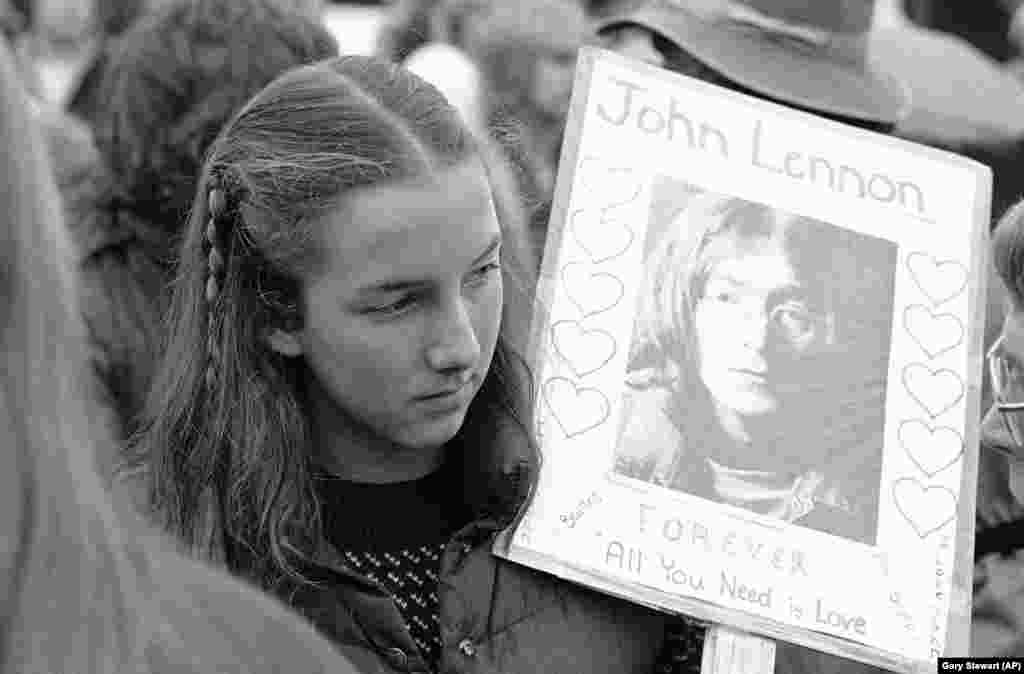 O tânără din Tacoma poartă un portret al fostului Beatles la serviciul religios dedicat lui John Lennon în Seattle Center, duminică, 14 decembrie 1980.
