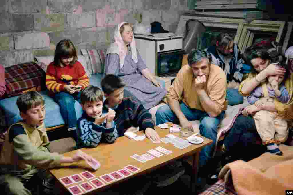 A family takes shelter in a cellar in Sarajevo on June 6, 1992, as shells fall on the Bosnian capital. The fighting continued, despite a UN-brokered deal to reopen the airport and for Serbian troops to withdraw from their barracks in the center of the city. 