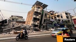 Commuters drive past a building that collapsed in the aftermath of the strong earthquake in Mandalay, Myanmar. 