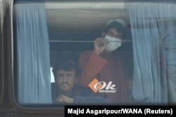 Afghans look out a a bus at the Dowqarun border crossing between Iran and Afghanistan in late August 2021.
