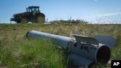 Un fragment dintr-o rachetă rusească zace pe un câmp în timp ce un fermier își lucrează pământul în regiunea Harkov din Ucraina, devastată de război.
