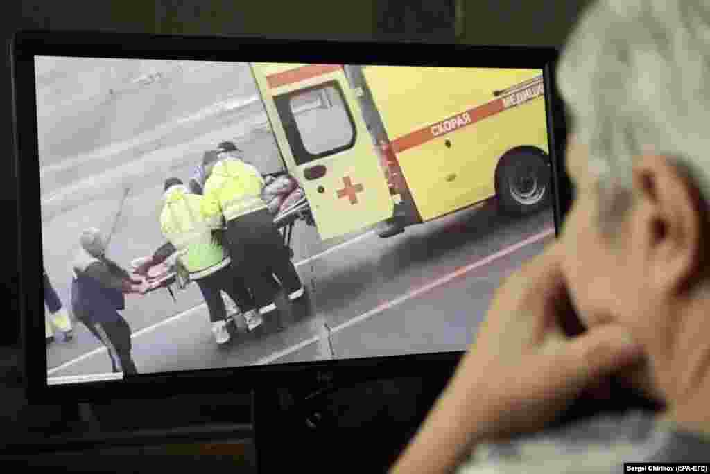 A person watches a video showing Navalny being carried on a stretcher by an ambulance team in Omsk after falling gravely ill from suspected poisoning while aboard a flight from Tomsk to Moscow on August 20, 2020.