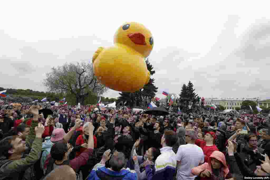 People play with a toy duck, adopted as a symbol of Medvedev's alleged wealth, during an anti-corruption rally in St. Petersburg on June 12, 2017. Medvedev became a target of anti-corruption protesters after a video released by opposition leader Aleksei Navalny purported to show his extravagant properties featuring helipads, a ski slope, and a house for ducks. 