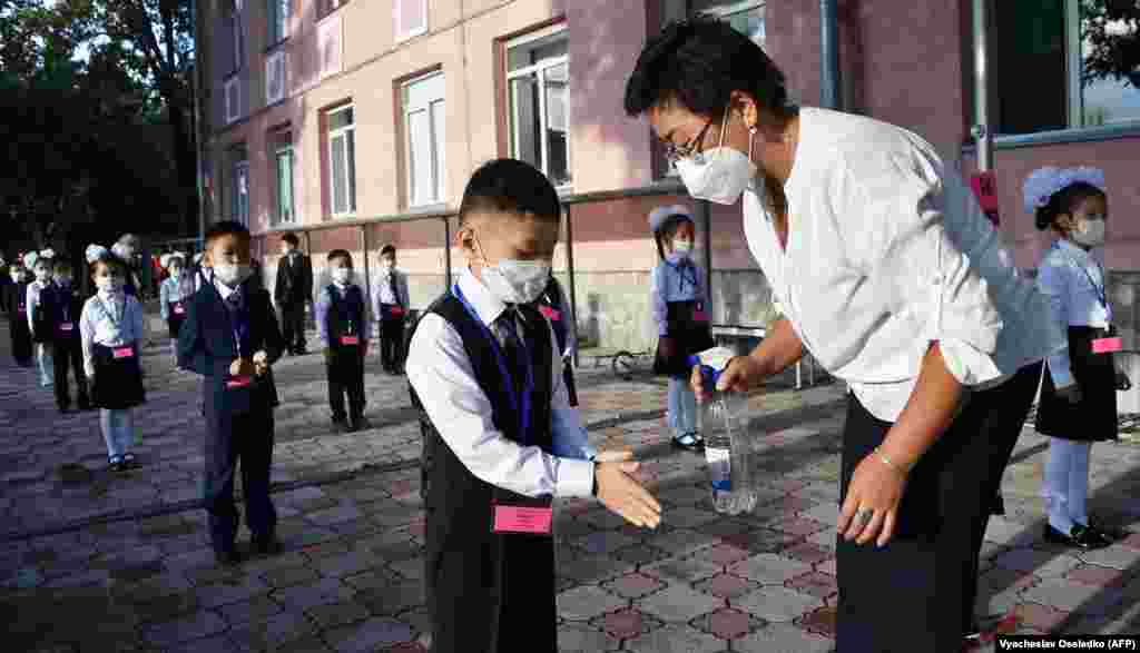O profesoară dezinfectează mâinile elevilor din Bishkek, Kîrgîzstan, în prima zi de școală, 1 septembrie.