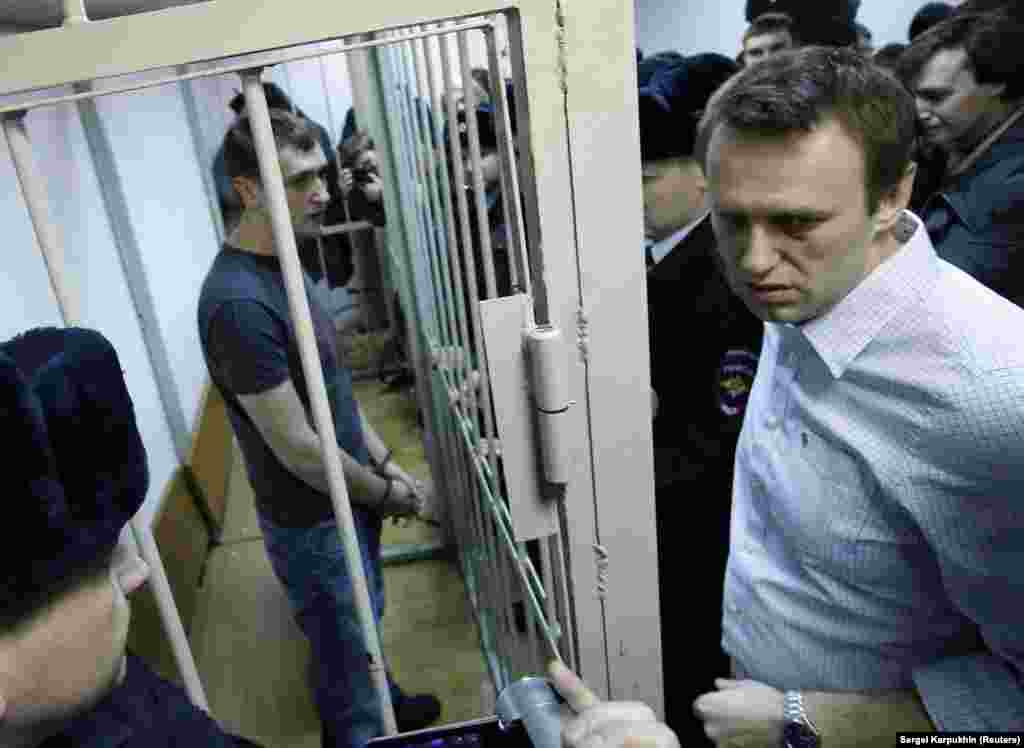 Navalnîi și fratele său Oleg (după gratii) în timpul unei audieri judecătorești de la Moscova, în decembrie 2014. Frații au fost condamnați pentru furtul a aproximativ 500.000 de dolari de la firme rusești. Aceștia au respins acuzațiile. Sentința lui Alexei Navalnîi a fost suspendată, dar fratele său și-a ispășit pedeapsa completă de 3 ani și jumătate, fiind eliberat în iunie 2018. 