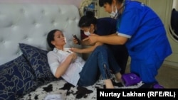 Medics examine Kazakh activist Saule Abildakhanqyzy after she said she was assaulted in Almaty on June 5.