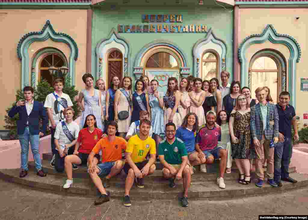 The group pose with a group of unwitting Russian high-school students on their graduation day. 