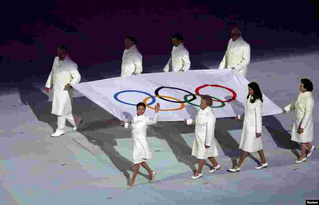 The Olympic flag is carried into the stadium. 
