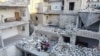 O familie reunită în ruinele unui bloc distrus. Orașul Ariha, provincia Idlib, Siria, 4 mai 2020