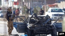 An Afghan soldier stands next to the site of a car-bomb attack in Kabul on November 13.