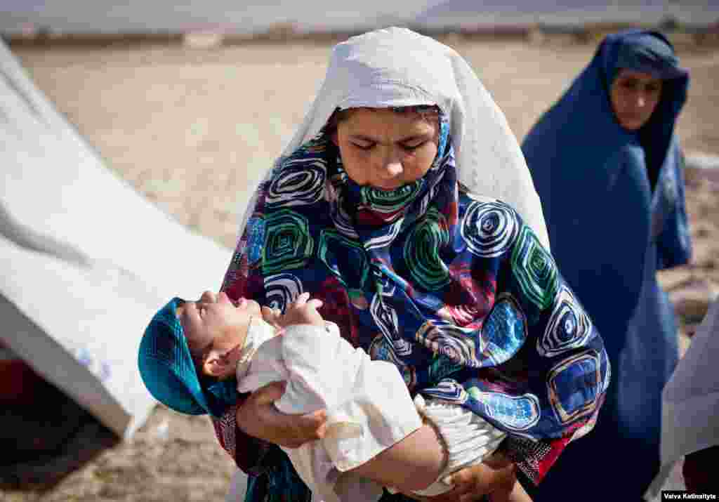 Homayra, a widow carrying her paralyzed child, lives in a makeshift refugee camp outside Mazar-e Sharif, Balkh Province.