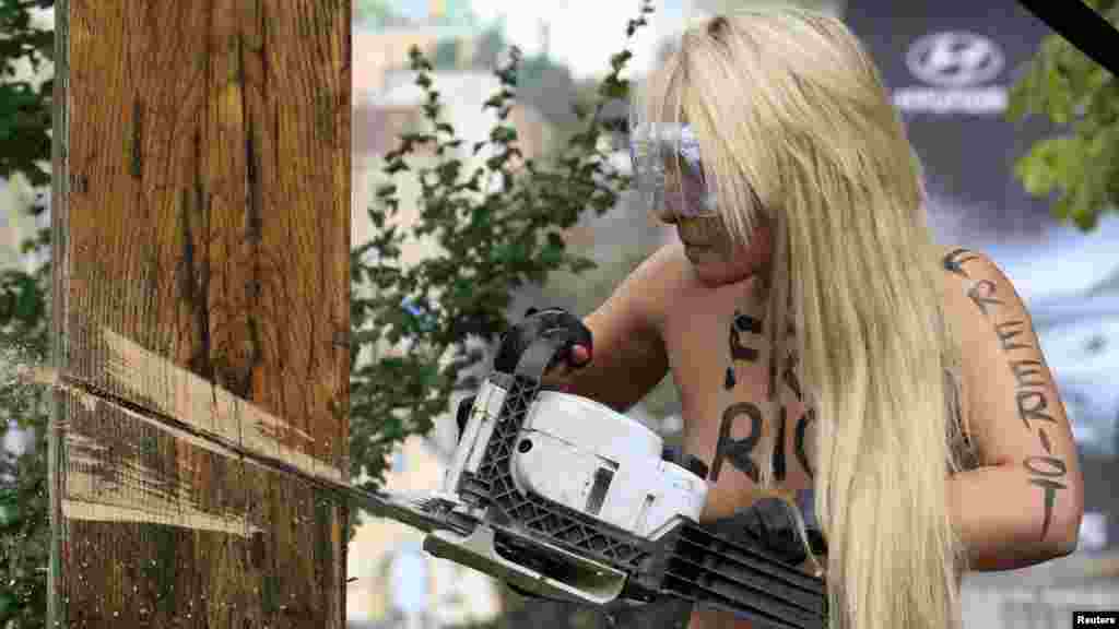 An activist from the women's rights group Femen uses a chainsaw to cut down a cross erected in memory of victims of political repression under Stalin in Kyiv to protest the Pussy Riot case.