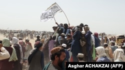 People wave Taliban flags as they drive through the Pakistani border town of Chaman on July 14 after the Taliban claimed it had captured the Afghan side of the crossing at Spin Boldak.