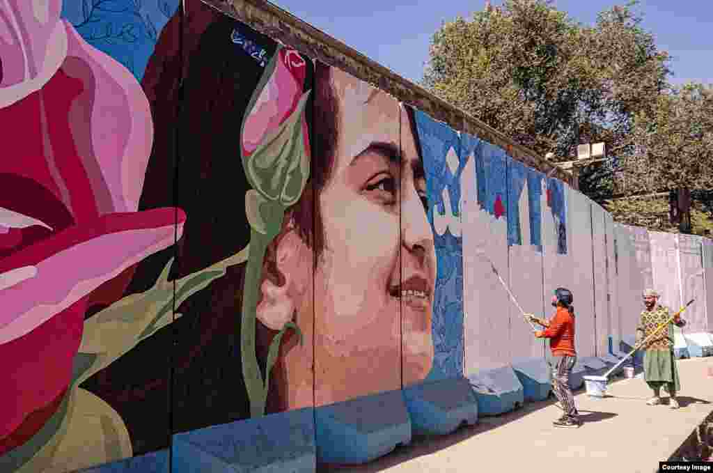 Workers paint over a mural featuring a young woman’s face. The men are professional sign writers, who later painted various slogans and pro-Taliban murals over the wall. The painters said they had been hired by the Taliban for the job. 