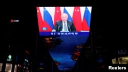 Russian President Vladimir Putin is seen on a giant screen broadcasting news footage of a virtual meeting between him and Chinese President Xi Jinping at a shopping mall in Beijing on December 15.