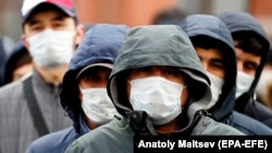 Migrant workers wearing face masks queue outside a migration control center in St. Petersburg on April 3.